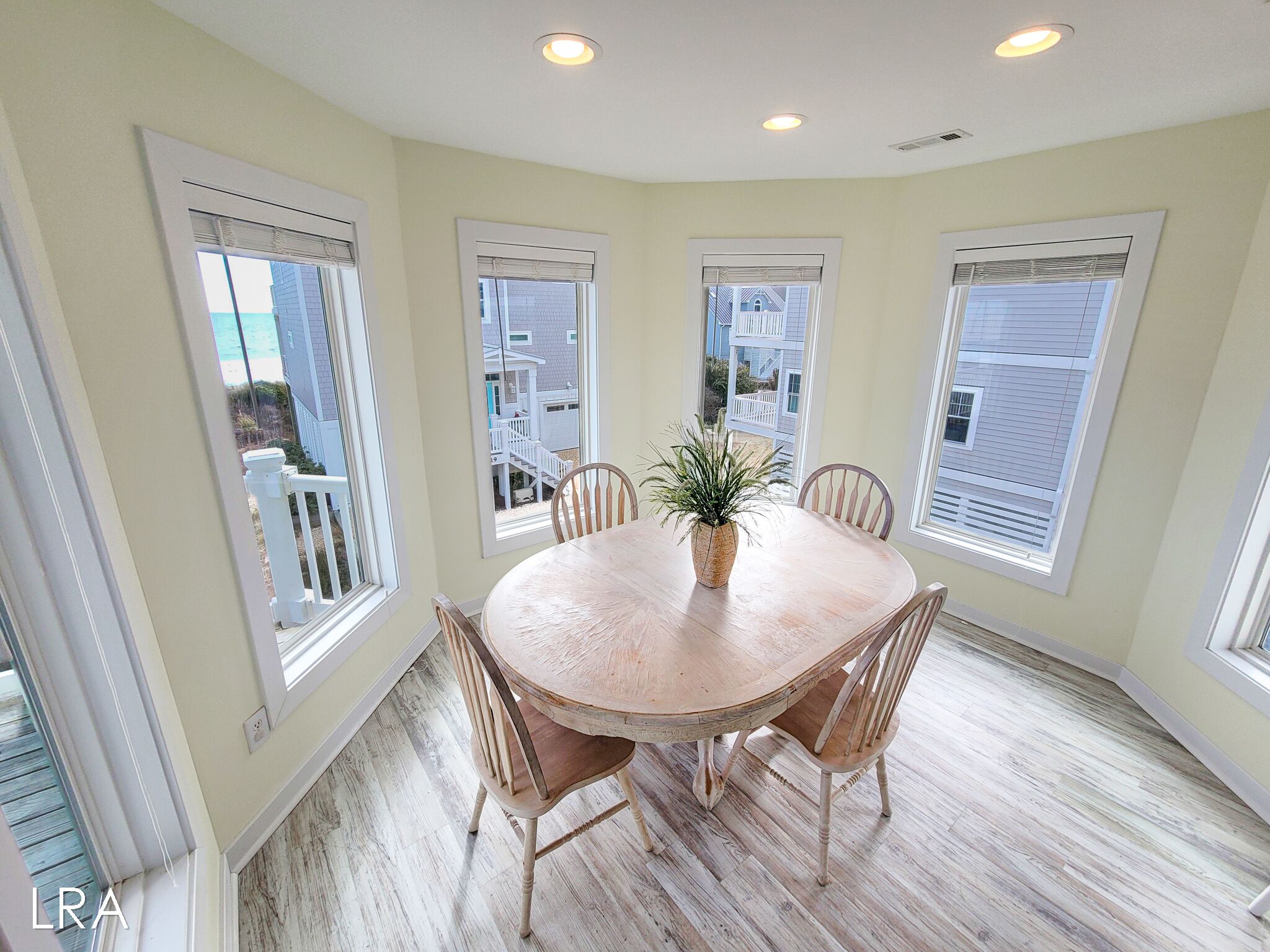 A dining area with a round wooden table, six chairs, and a potted plant.