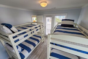 Una habitación con literas, una puerta con ventanal y una lámpara en el techo.