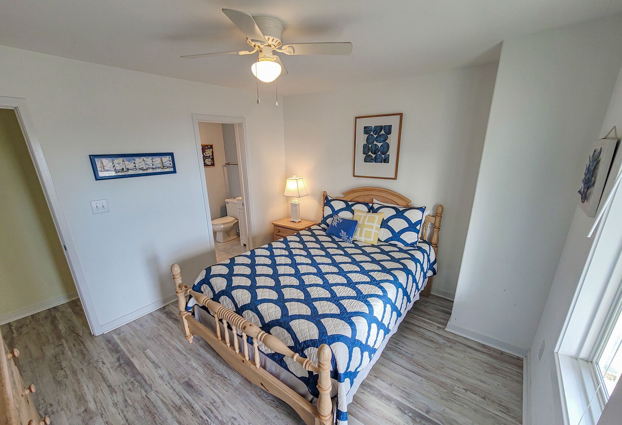 Une chambre à coucher avec un lit en bois, un ventilateur de plafond et une table de chevet avec une lampe.