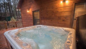 Un jacuzzi frente a una cabaña de madera con un porche.