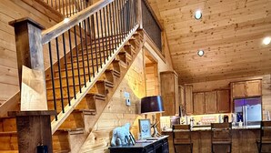 Un interior de madera con una escalera, una zona de cocina y una barra.