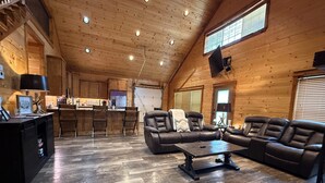 Un interior espacioso de madera con un amplio sofá seccional en forma de L, un comedor y una cocina.