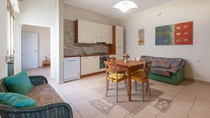 Eine moderne Küche mit weißen Schränken, einem eingebauten Herd und einem Essbereich mit Holztisch und Stühlen.