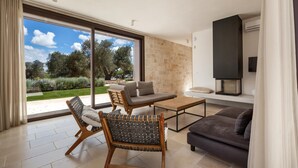 A modern living room with a sofa, two chairs, a coffee table, and a fireplace. - 3155 Villa Pietralunga by Perle di Puglia (Ostuni)