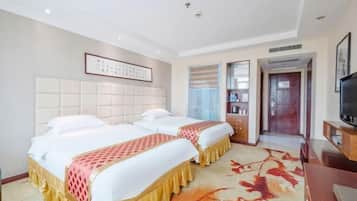 A hotel room with two beds, a television, and a bookshelf.