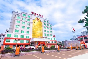 Un hotel de varios pisos con una sección central amarilla destacada y señalización roja.