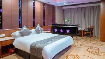A hotel room with a bed, a desk, a chair, and a television.
