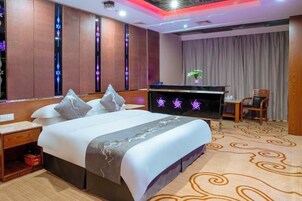 A hotel room with a bed, a desk, a chair, and a television.