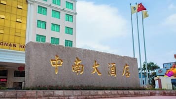 A hotel sign with Chinese characters, a flag, and a building in the background.