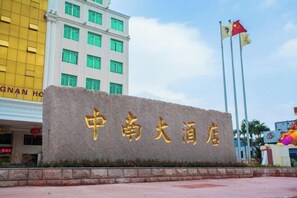 A hotel sign with Chinese characters, a flag, and a building in the background. - Zhongnan Hotel (Nan'an)