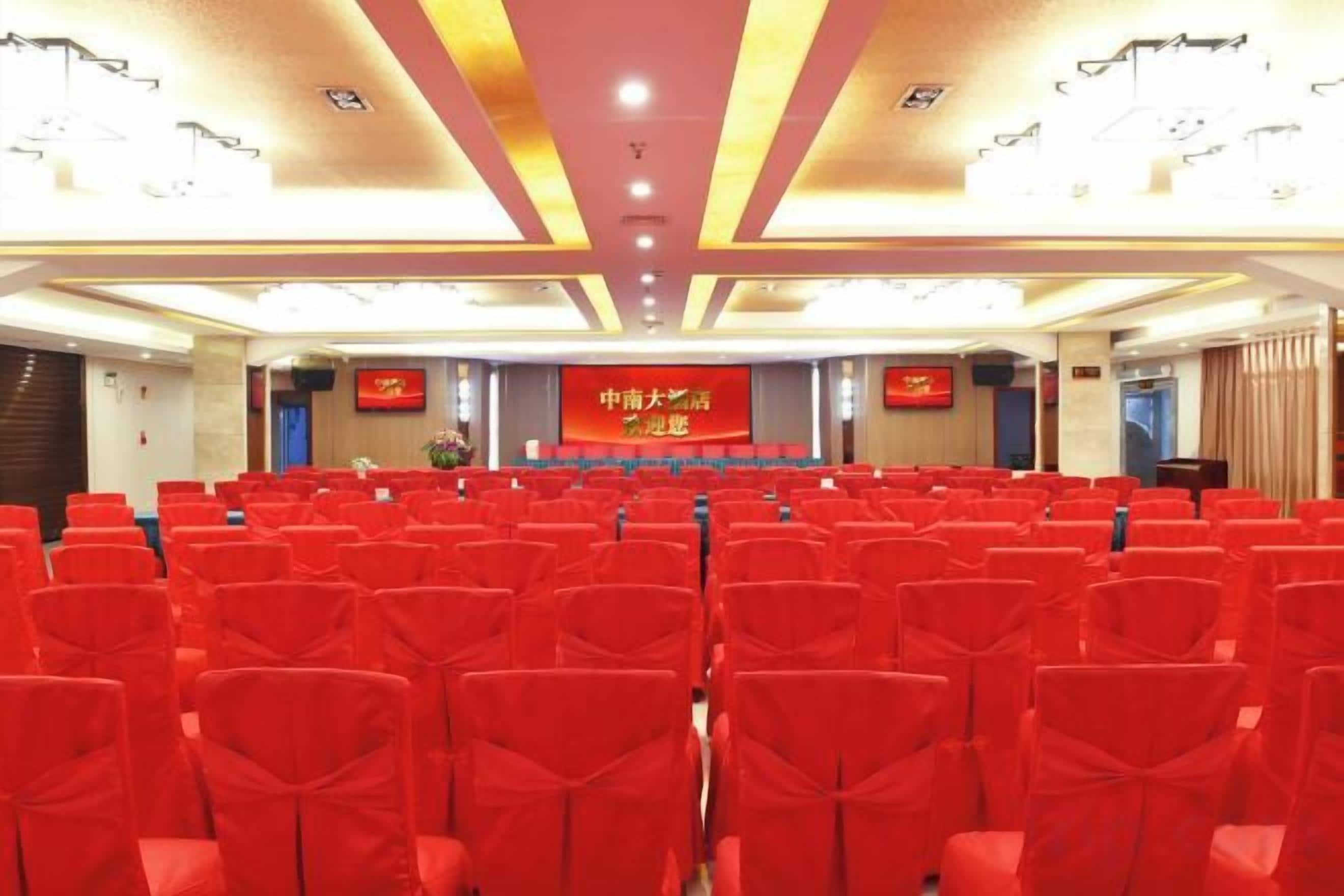 A conference room with rows of chairs, a stage with a podium, and a banner.