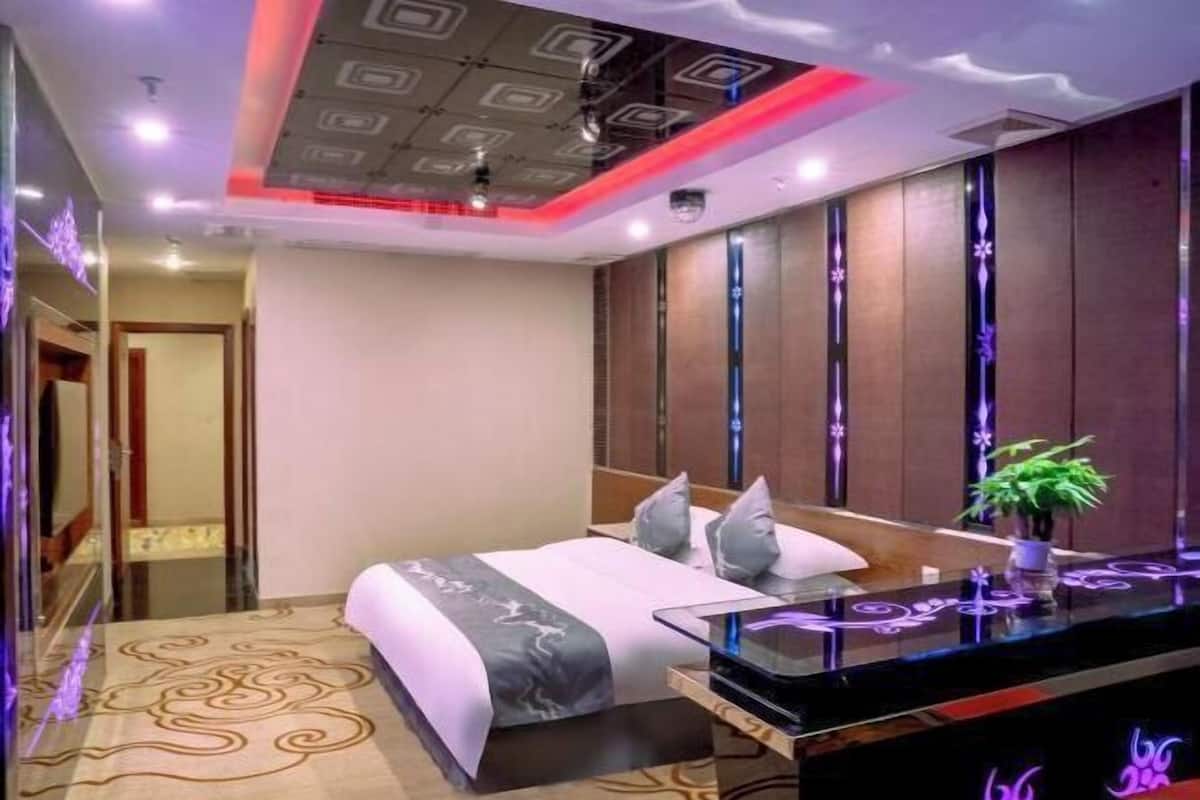 A modern hotel room with a large bed, a glass desk, and a decorative mirror.