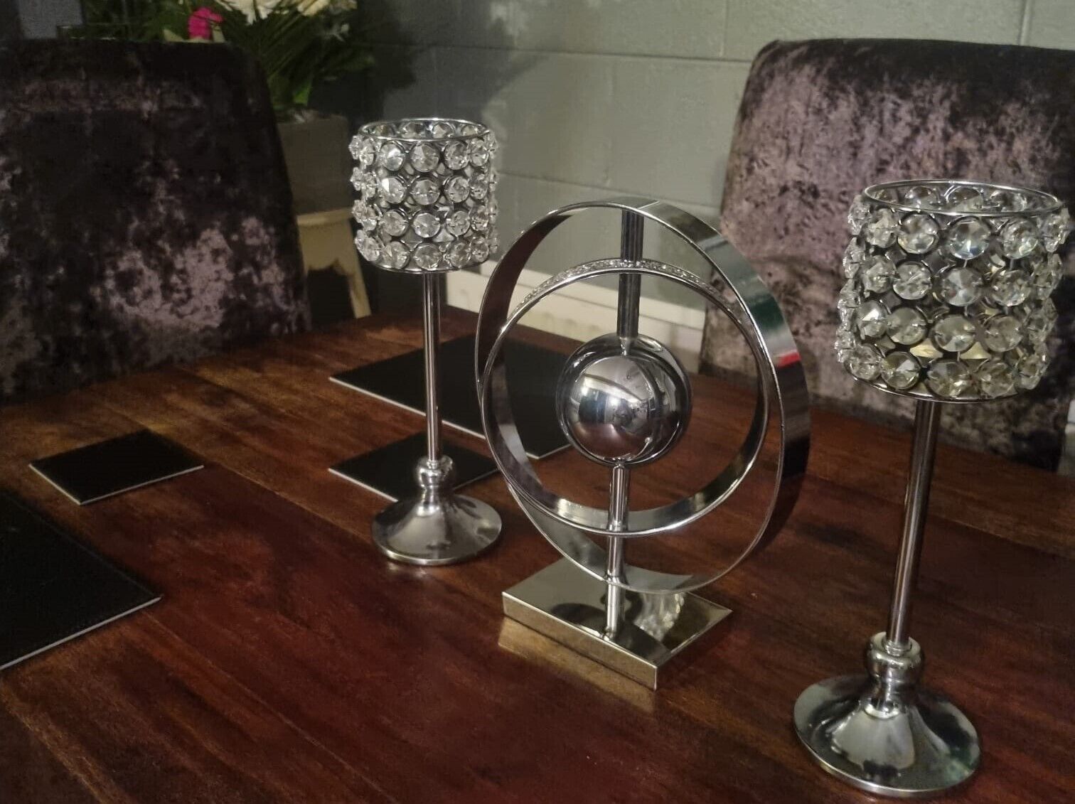A wooden table with three decorative silver stands, each topped with a crystal-like structure.