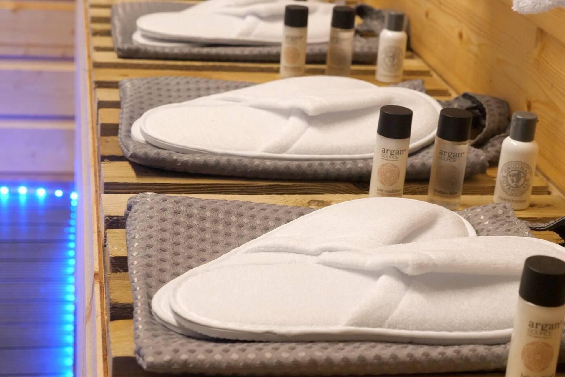 Una exhibición de pantuflas blancas y botellas de aceite de argán sobre un estante de madera.