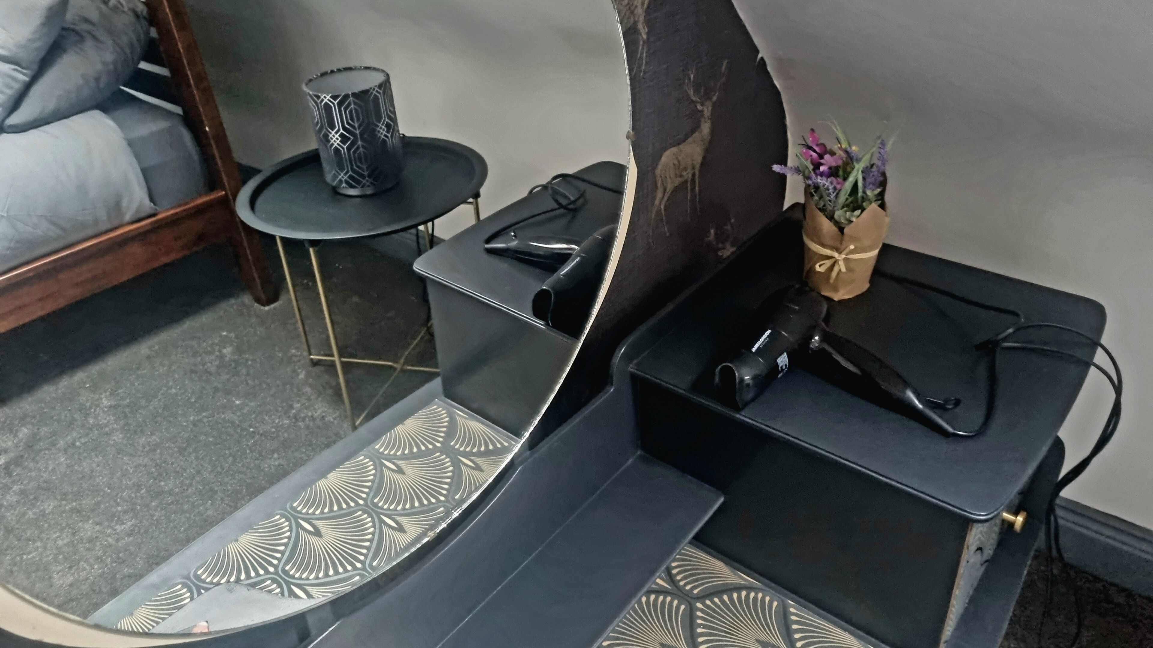 Une petite pièce comprenant un lit, une petite table ronde et un vase décoratif avec des fleurs.