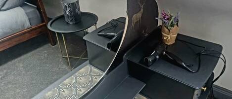Une petite pièce comprenant un lit, une petite table ronde et un vase décoratif avec des fleurs.