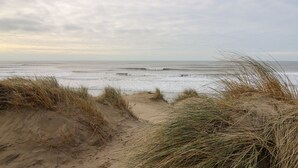 A beach with sand dunes and a view of the ocean. - Gwent 74 (Borth)