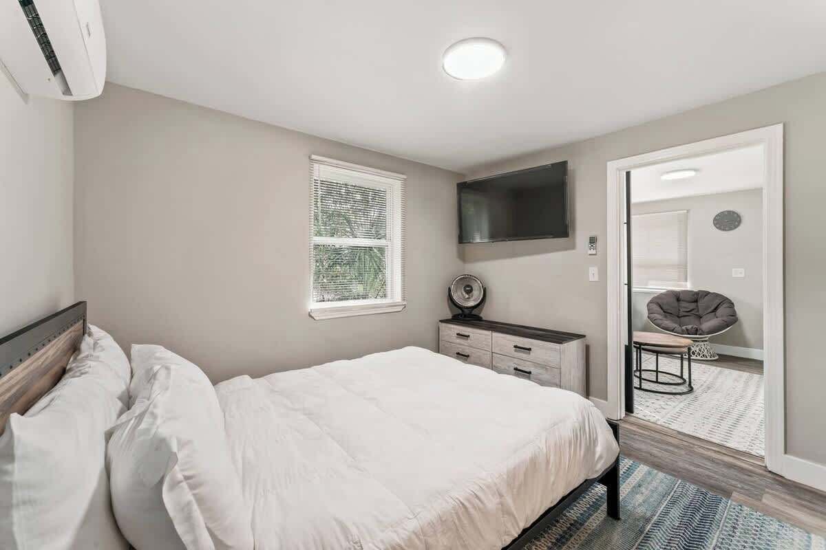 A bedroom with a bed, a dresser, a mirror, and a window.