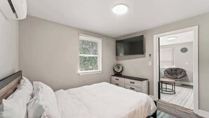 A bedroom with a bed, a dresser, a mirror, and a window.