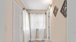A hallway with white doors, a bench, and decorative wall art.