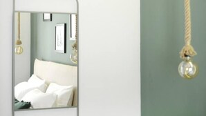 Un dormitorio con una cama, una lámpara colgante y un espejo en la pared.