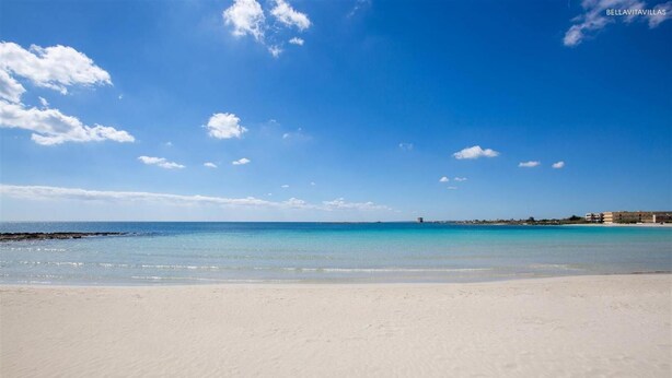 Une plage à l’eau d’un bleu limpide et au rivage sablonneux.