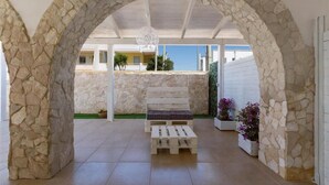 Un arc en pierre mène à un patio agrémenté d’un banc et de plantes en pot.