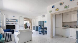 Un salon moderne comprenant un canapé, un téléviseur et un coin repas avec des chaises et une table.