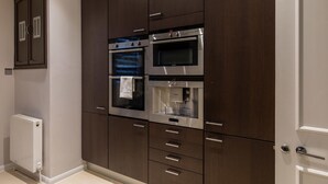 Une cuisine moderne avec des meubles en bois foncé, des appareils électroménagers en acier inoxydable et un four encastré.