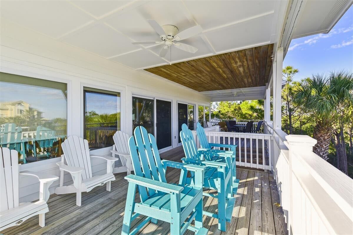 A covered outdoor area with white Adirondack chairs and a wooden deck.