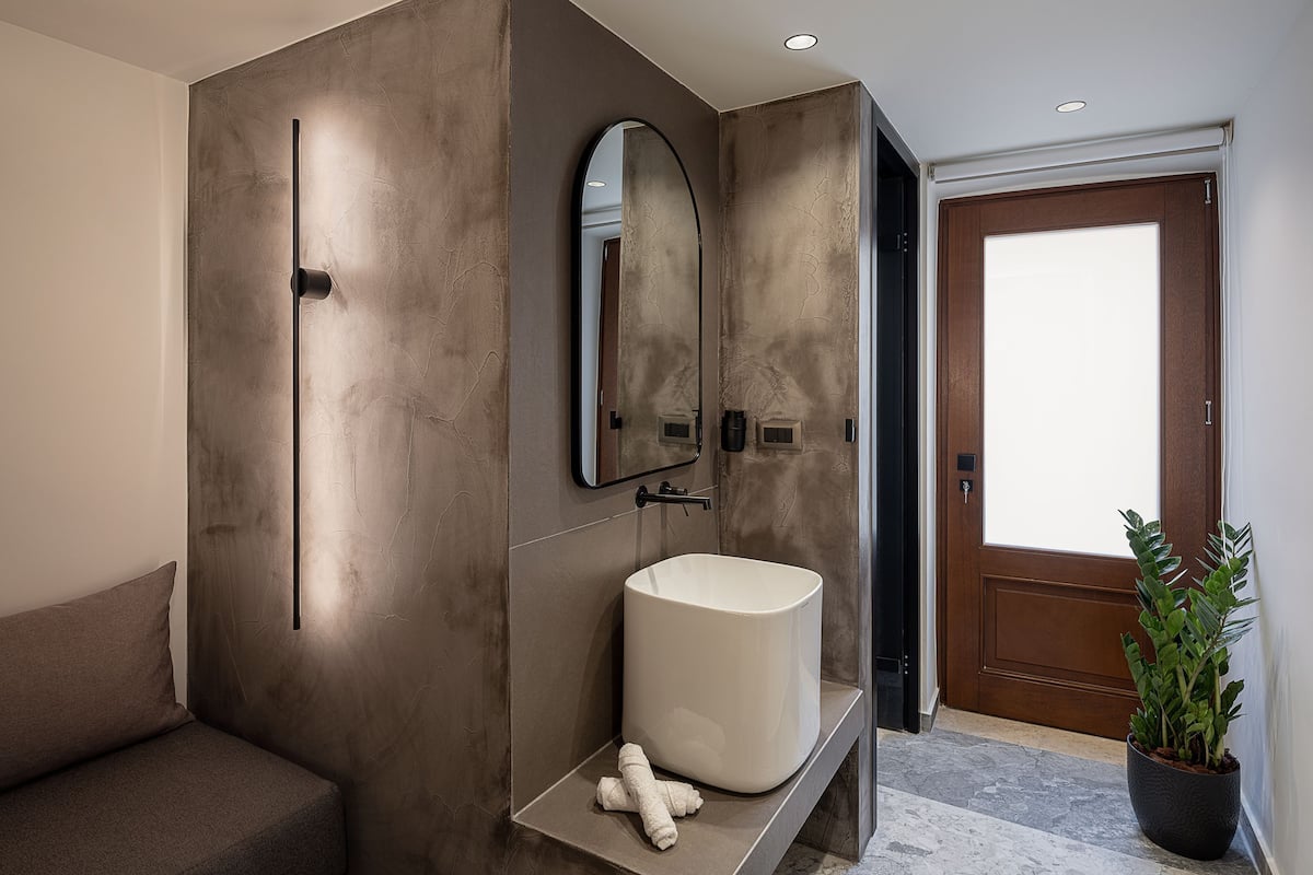 A modern bathroom with a large mirror, a white sink, and a towel on the counter.