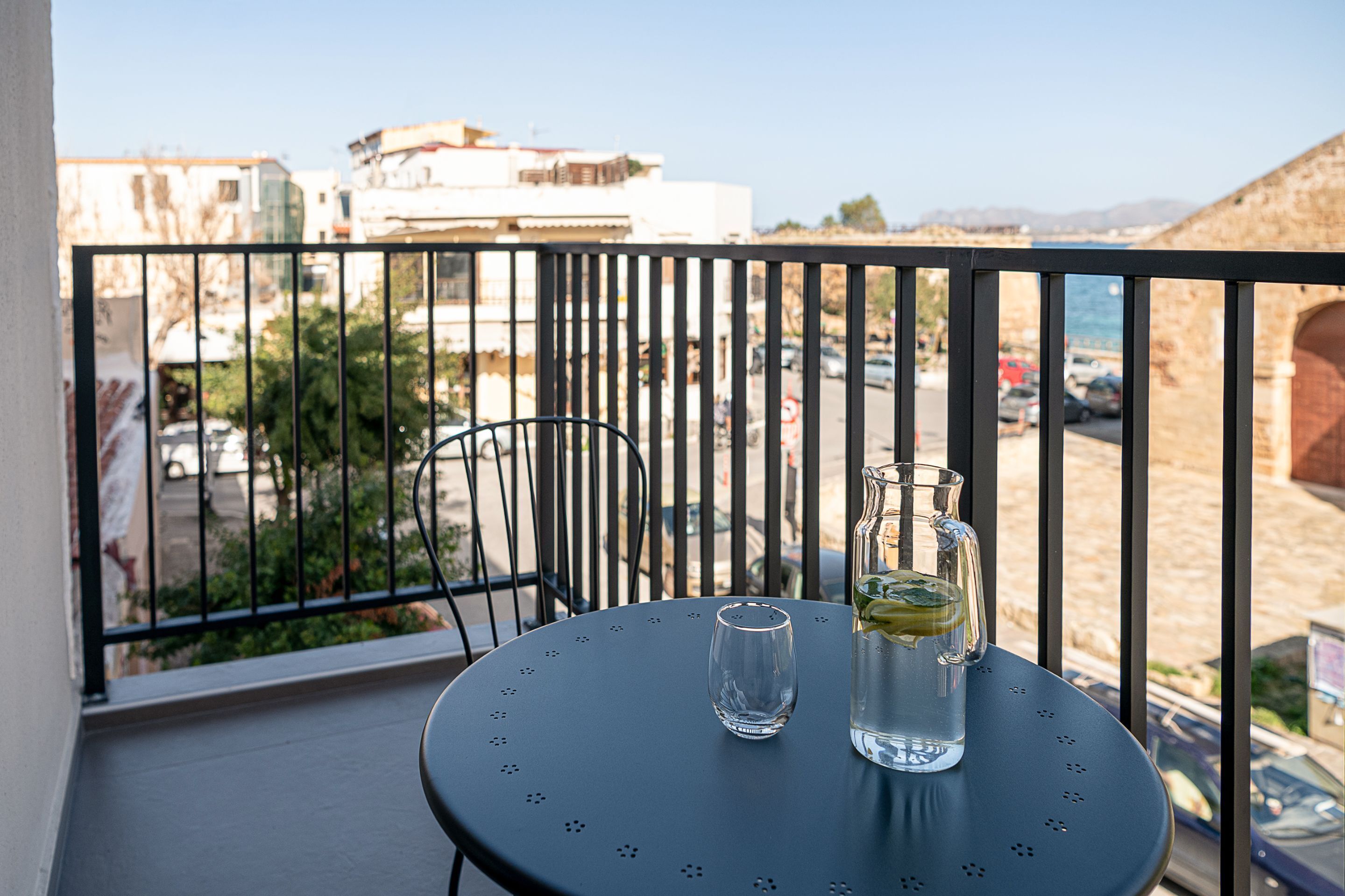 Een balkon met een tafel, een stoel en een waterkan.