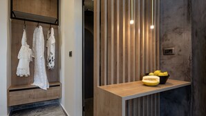 A modern bathroom with a wooden vanity, a towel rack with white towels, and a bowl of fruit on the counter. - Ethos Suites (Chania)