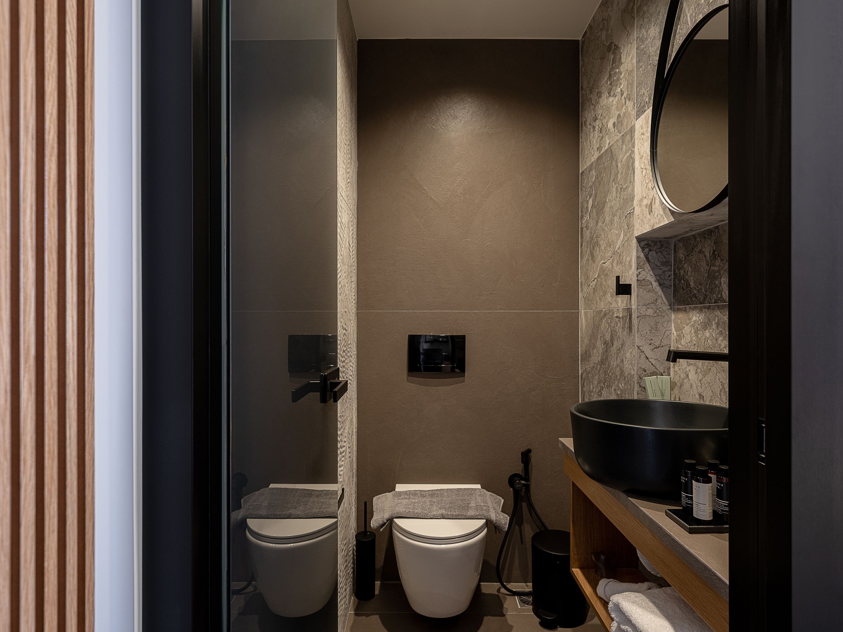 A modern bathroom with two toilets, a large mirror, and a sink with a basin.