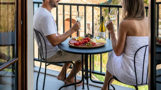 A couple dining at a table with a view of the sea and hills. - Ethos Suites (Chania)