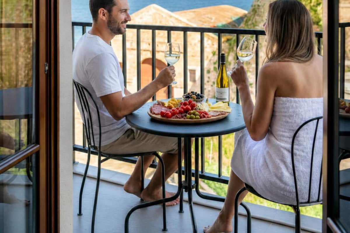 A couple dining at a table with a view of the sea and hills.
