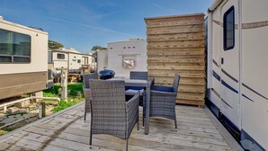 Een terras met rieten meubels en een barbecue, omringd door campers.