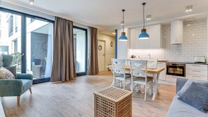 A modern living room with a sofa, a coffee table, and a dining area with chairs and a table. - Naviflat- Luxury Sopot Residence Okrzei 21 by Lion Apartments (Sopot)