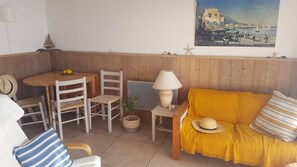Una habitación acogedora con un banco de madera, un sofá amarillo, una mesita con una lámpara y un cuadro en la pared.