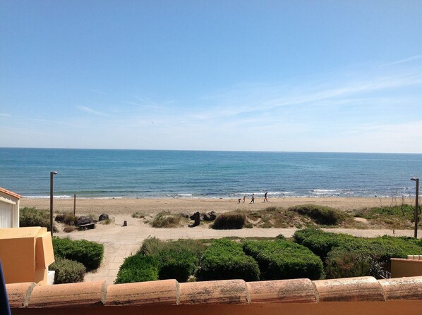 A beach with a clear view of the ocean, a paved walkway, and some greenery. - Absolute beach front apartment Plage Roquille Fabulous Views Direct beach access (Agde,)