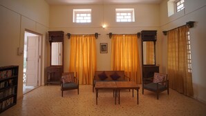 A spacious room with a large window, a fireplace, a sofa, two armchairs, and a bookshelf. - Dariya mahal Gopnath (Talaja)