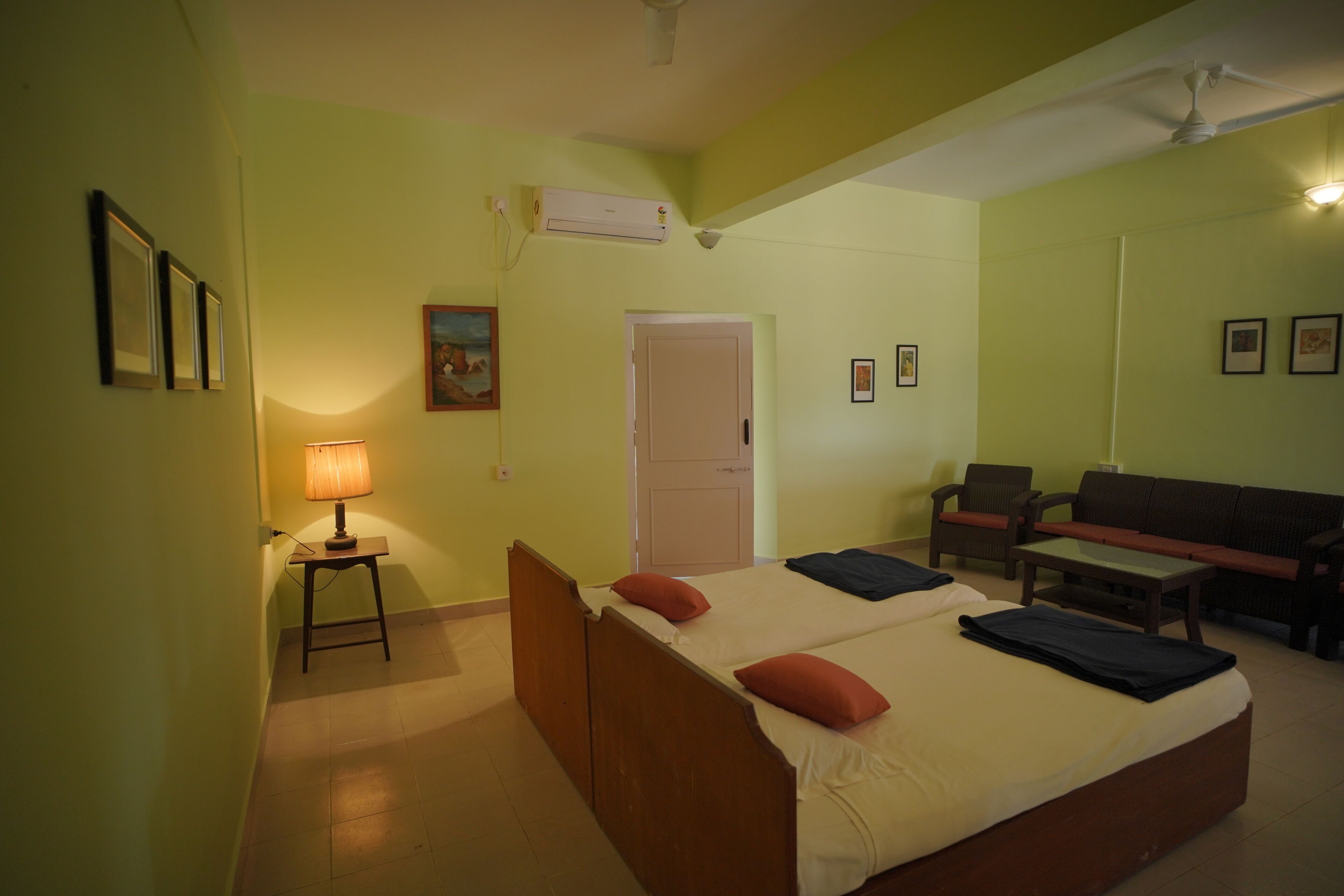 A room with two beds, a desk, a chair, and a sofa.