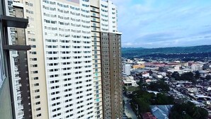 Un immeuble de grande hauteur, doté de nombreux étages, d’un espace de stationnement et offrant une vue sur le paysage urbain en arrière-plan.