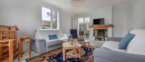 Ein modernes Wohnzimmer mit einem grauen Sofa, einem blauen Sessel, einem Holztisch und einem gemusterten Teppich.