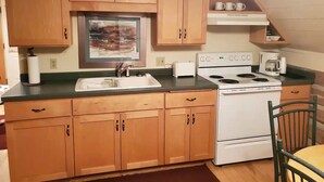 A kitchen with wooden cabinets, a stove, a sink, and a toaster. - Tamarack Point Homestead (Arcadia)