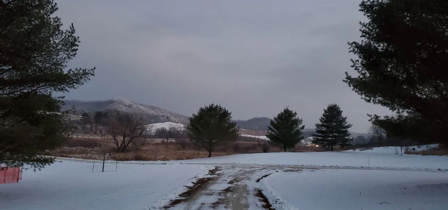 A snowy landscape with a clear path leading through a rural area.