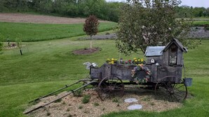 A rustic wooden structure with a small shed, surrounded by a well-maintained grassy field and a tree. - Tamarack Point Homestead (Arcadia)