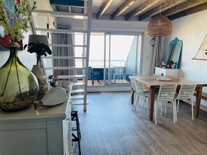 Eine moderne KĂŒche mit Holztisch und -stĂŒhlen, einem weiĂen Schrank und einer hĂ€ngenden Korbscharnik.