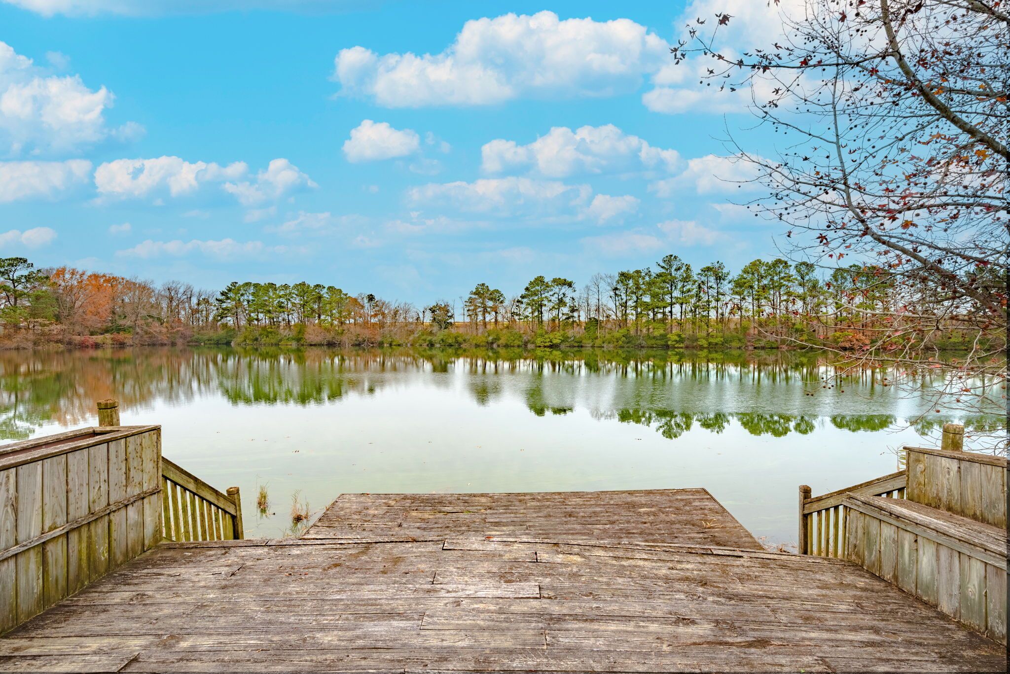 A wooden dock leading to a calm lake surrounded by trees.