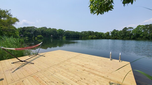 A wooden dock extending into a calm lake, surrounded by dense greenery.